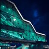 Современный терминал аэропорта Барселоны Эль-Прат с футуристичной бирюзовой подсветкой ночью — лидера рейтинга World Consumer Airport Index