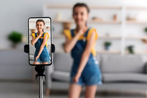 Девочка-подросток танцует на камеру смартфона для съемок блога
